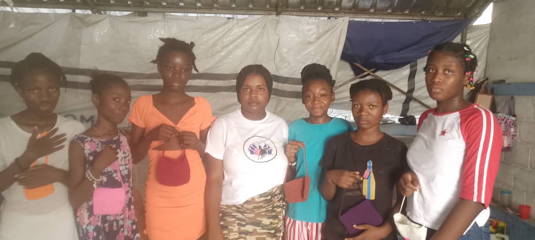 Young girls in Haiti holding handmade bags they crafted through a community workshop.