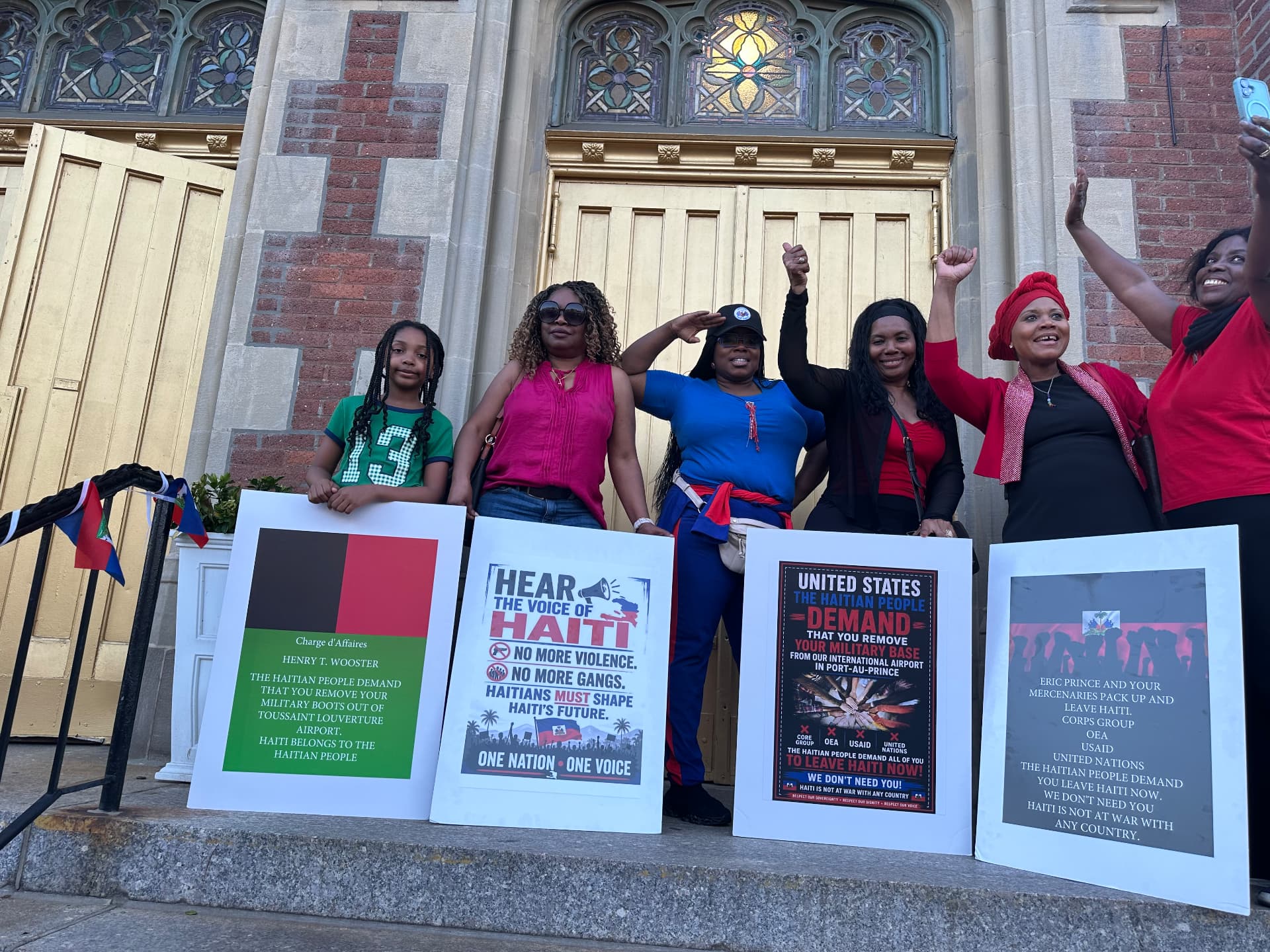 Community members rally with signs demanding freedom and dignity for Haiti.