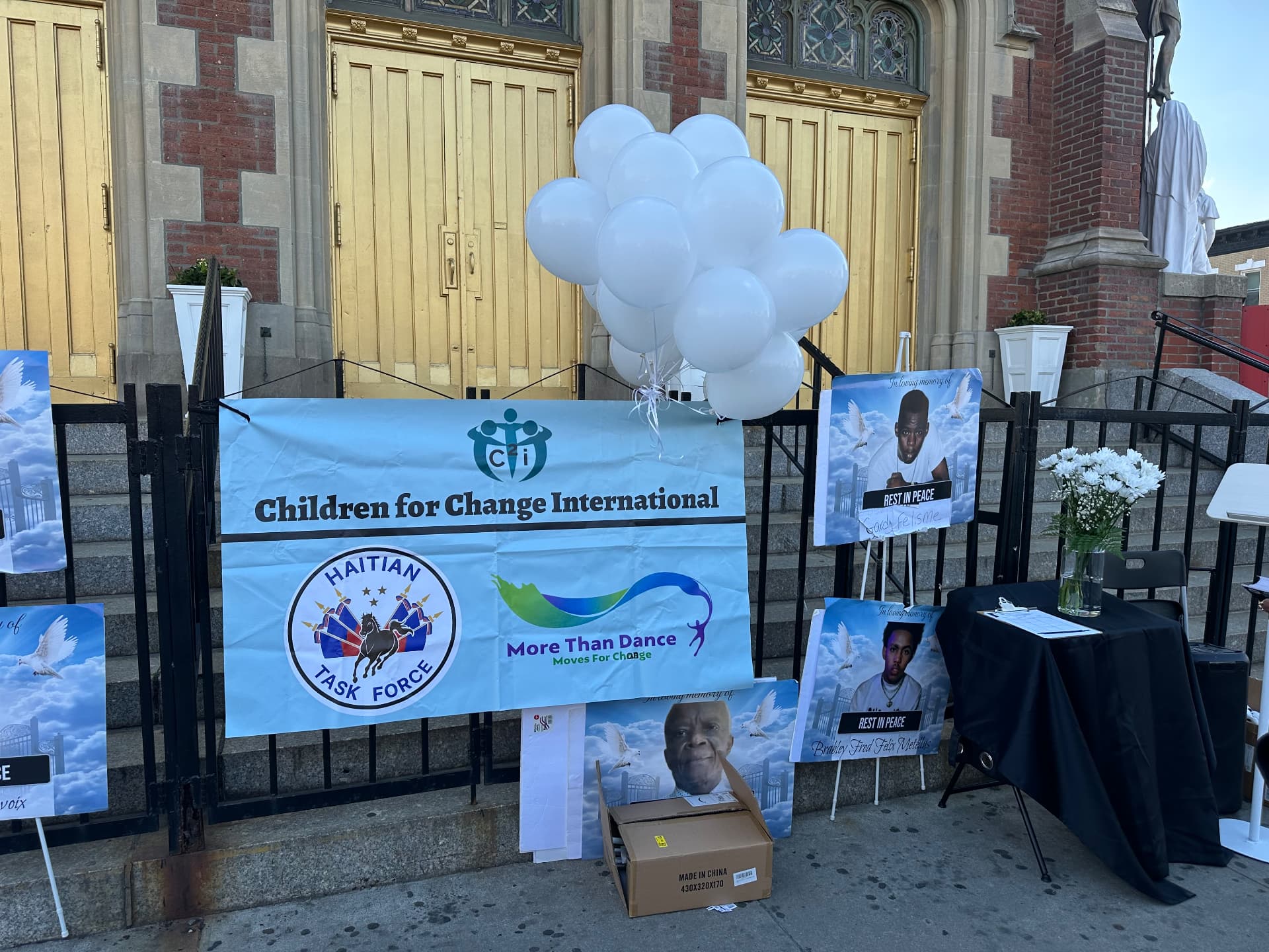 Memorial banner with Haitian Taskforce and partner logos beside portraits of loved ones lost to violence.